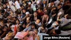 Afghans gather outside the passport office in Kabul on October 6 after Taliban officials announced they would start issuing passports again.