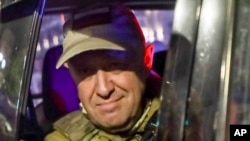 Wagner chief Yevgeny Prigozhin smiles for cameras as he departs Rostov-on-Don, Russia, on June 24 after calling his mercenary troops to stand down on a "march of justice" to Moscow.