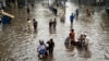 People make their way through a flooded road caused by heavy monsoon rainfall in Lahore, Pakistan, on July 26.