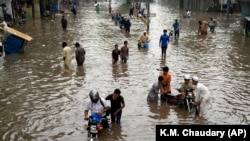 People make their way through a flooded road caused by heavy monsoon rainfall in Lahore, Pakistan, on July 26.