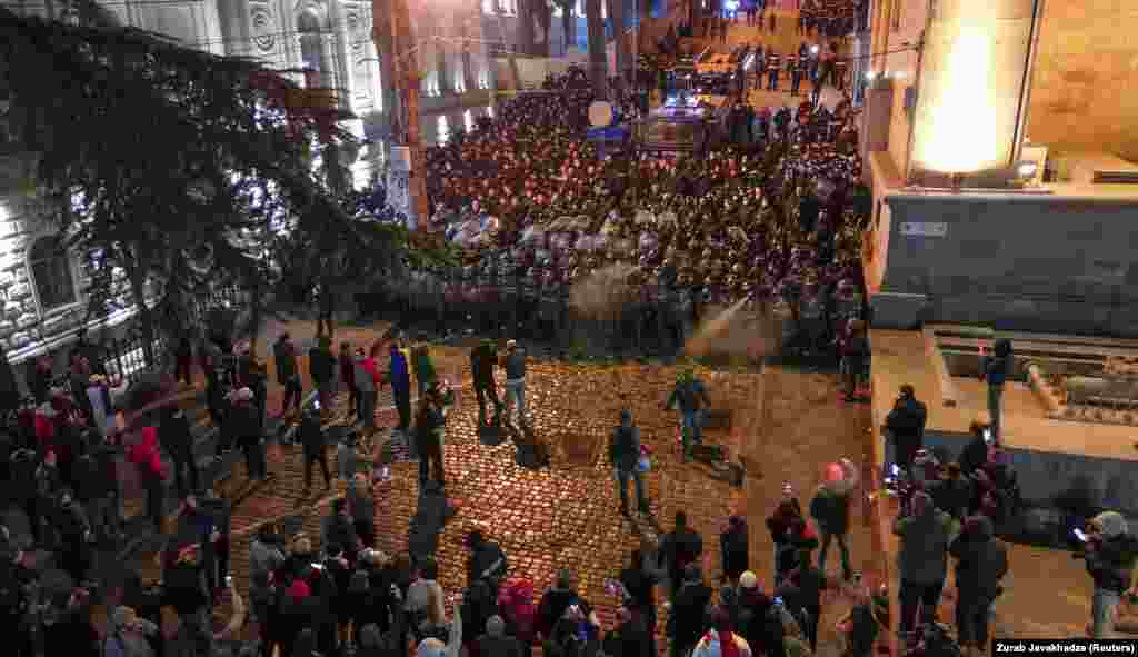 A wall of police faces protesters on a street that leads to the rear entrance of Georgia&#39;s parliament building (seen on right).&nbsp;