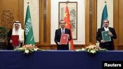 Wang Yi (center) holds up a March 2023 deal in Beijing with the secretary of Iran's Supreme National Security Council, Ali Shamkhani (right), and Saudi State Minister Musaad bin Muhammad al-Aiban.