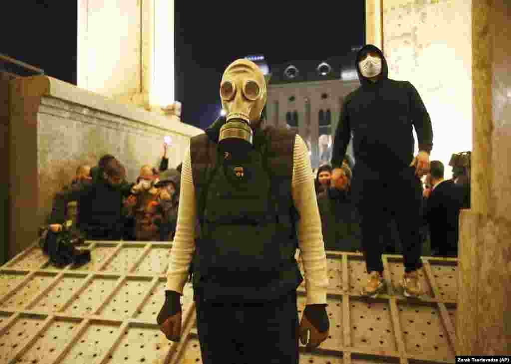 A protester wears a gas mask at the entrance to the parliament building, on Tbilisi&#39;s Shota Rustaveli Avenue, after a steel barrier designed to stop protesters was toppled.&nbsp;