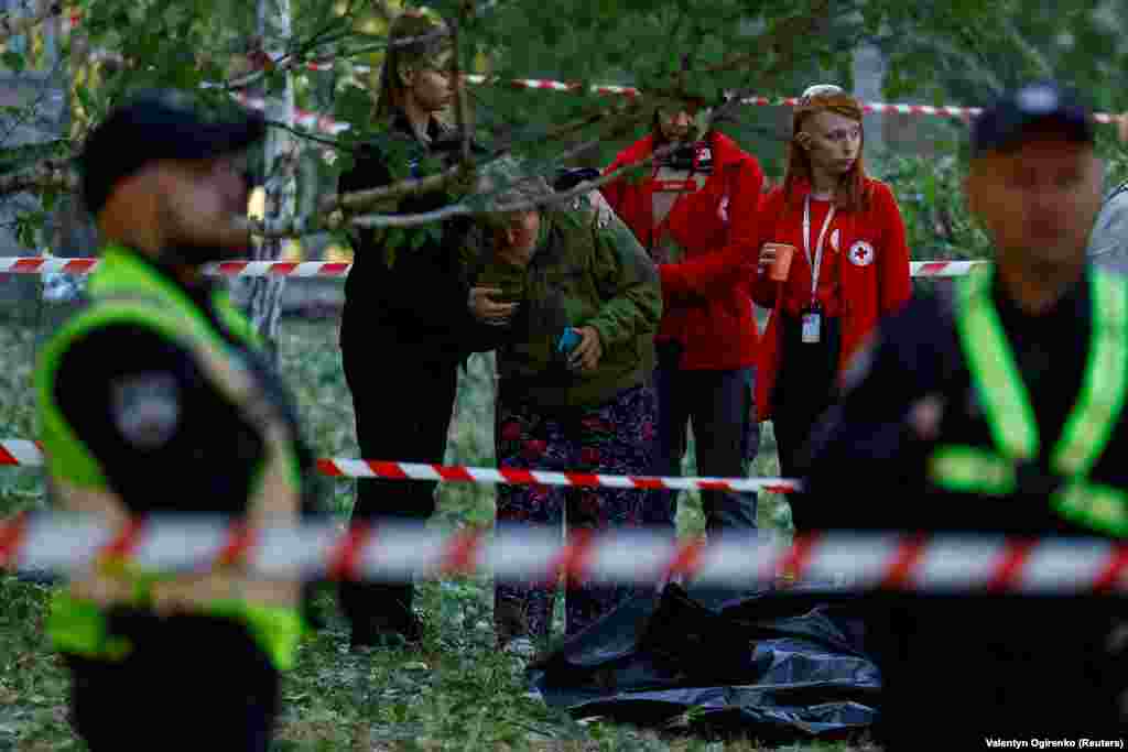 The woman is comforted by emergency responders at the scene. Lyudmyla, a local resident who declined to provide her surname said, &ldquo;Everything happened very fast, within probably 15 minutes: the air-raid siren, then the air-defense forces fired, then a cloud of brown smoke.&quot;