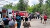 People stand outside a residential building damaged by shelling in the Russian-occupied Ukrainian city of Luhansk on June 7. 