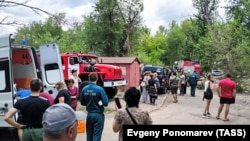 People stand outside a residential building damaged by shelling in the Russian-occupied Ukrainian city of Luhansk on June 7. 