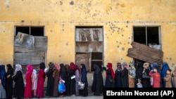 Afghan women wait to receive food rations distributed by a humanitarian aid group in Kabul.