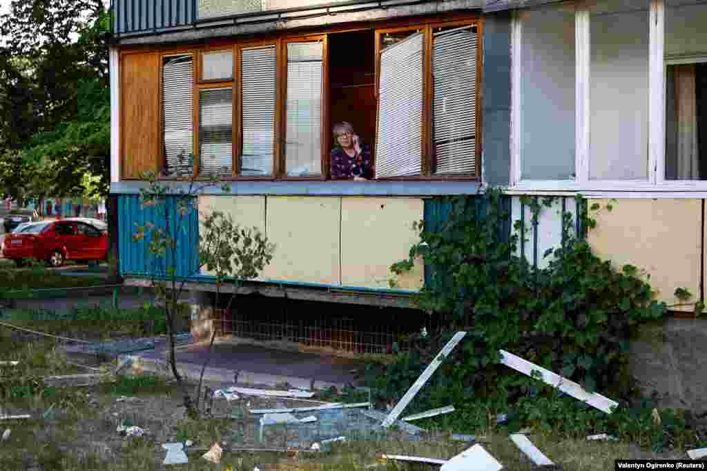 A woman whose apartment was damaged during the attack speaks on the phone as emergency responders work nearby. &nbsp; &nbsp; &nbsp;