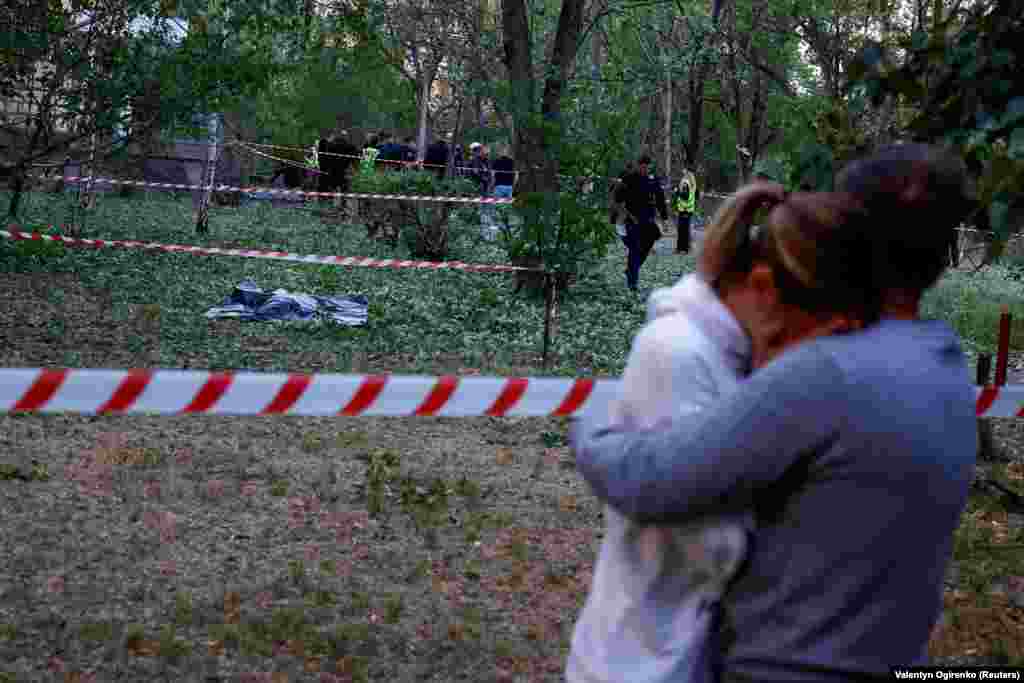 A man comforts a woman near the body of a person killed by falling debris near a municipal clinic. At least three people were killed in the attack, according to local officials. Ukraine&#39;s air force said air defenses shot down all 10 ballistic and Iskander cruise missiles launched from Russia&#39;s Bryansk region in the 18th attack on the capital since the start of May.