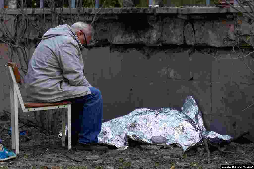 A man sits next to the body of his granddaughter, age 9, who was killed along with her mother during the missile strike.