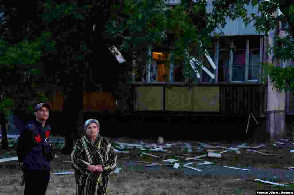 Residents stand near a damaged apartment building following the Russian missile attack on June 1.&nbsp; Police said a medical clinic, a kindergarten, residential buildings, and cars were damaged in the strike.