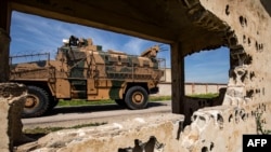 An army vehicle drives past the ruins of a building during a Turkish and Russian military patrol in the countryside of Rumaylan in Syria's northeastern Hasakeh Province bordering Turkey, on April 27.