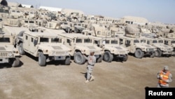 U.S. soldiers check military vehicles to be shipped as troops prepare to pull out of a military base in Nassiriya, Iraq.