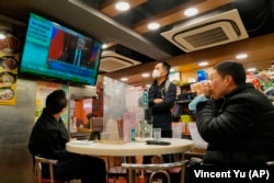 People in a Hong Kong restaurant watch a broadcast as Russian troops invade Ukraine on February 24, 2022.