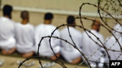 A group of detainees kneels during early morning Islamic prayer at the Guantanamo camp