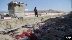 A Taliban fighter stands guard at the site of the August 26 twin suicide bombings that killed scores of people at Kabul airport in 2021.