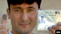 An Afghan man shows his thumb marked with ink and his voter's pass after registering to vote in the country's presidential poll, now scheduled for August 20.