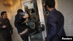 A protester kicks in a door at the British Embassy compound in Tehran on November 29.