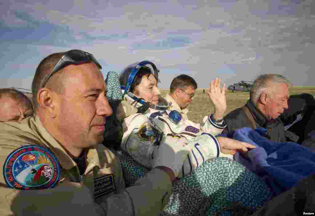 Revin waves as he is carried away shortly after landing. The space travelers are placed on reclining chairs to ease their return to gravity.