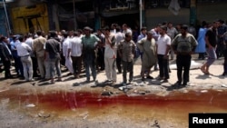 Residents stand next to a pool of blood and water after a car-bomb attack in Karbala on April 29.