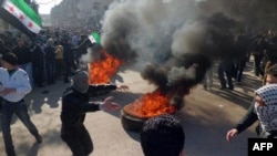 A handout picture released by Local Coordination Committees in Syria shows protesters burning tires and waving independence flags during an antigovernment demonstration in a Damascus suburb on February 4.