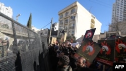 Iranian riot police block a street leading to the Saudi Embassy as protesters hold portraits of prominent Shi'ite Muslim cleric Nimr al-Nimr during a demonstration in Tehran on January 3 against his execution by Saudi authorities.