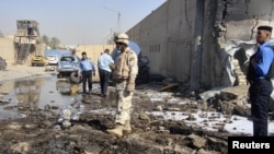 A soldier and policemen inspect the site of a bomb attack at a police station in Baghdad's Hurriyah district.