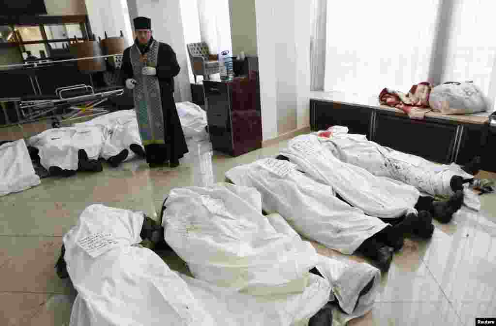 A priest stands in the lobby of the Ukraine Hotel near dead bodies of antigovernment protesters.