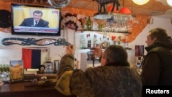 Ukrainians react as they watch a TV broadcast of ousted Ukrainian President Viktor Yanukovych's press conference on February 28.