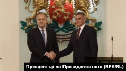 Bulgarian President Rumen Radev (left) and caretaker Prime Minister Stefan Yanev shake hands in Sofia after a new cabinet was sworn in on May 12. 