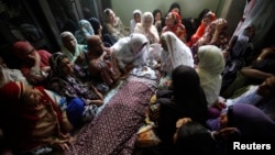 Mourners sit around the body of a boy who was killed in a bomb blast in Karachi in August.