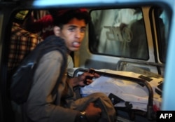 A young boy sits next to the body of a blast victim in an ambulance in Karachi early on August 7. The 11 killed were all younger than 15.