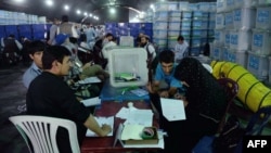 Afghan election workers sort ballot papers during an audit of the presidential runoff vote in the country's general election at a counting center in Kabul on August 25.