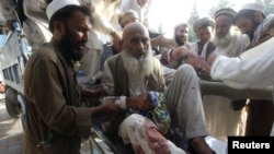 Men assist fellow Afghans injured in a bomb blast as they arrive at a hospital in Jalalabad in September.