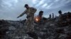 People walk among the debris at the MH17 crash site near the village of Hrabove in the Donetsk region on July 17, 2014.