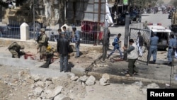 Afghan police and NATO troops inspect the site of a suicide attack in Faryab Province on April 4.