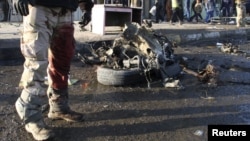 A wounded soldier stands near the remains of a vehicle used in a bomb attack in Sadr city in northeastern Baghdad on January 24.