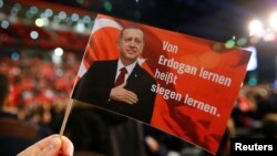 A man holds a flag showing Turkish President Recep Tayyip Erdogan that read's "Learning from Erdogan means learning how to win" during Prime Minister Binali Yildirim's speech in Oberhausen, Germany, on February 18.