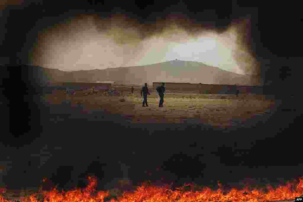 Afghan policemen walk beside a burning pile of opium products during an official ceremony in Kabul in 2007.