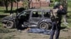 A police officer stands near a destroyed car and covered victim at the site of a Russian missile strike in the village of Zolochiv, Kharkiv region, Ukraine, on May 1.