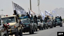 Taliban fighters atop vehicles with Taliban flags parade along a road in Kandahar on September 1 to celebrate after the United States completed its withdrawal from Afghanistan.