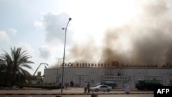 Protesters sit near a burning supermarket during a demonstration calling for jobs and reform in Sohar on February 28.