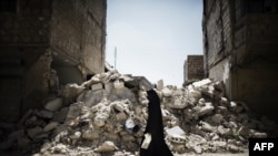 A Syrian woman walks past a destroyed building while reaching a food distribution centre in Aleppo earlier this month. 