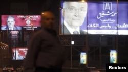 An Egyptian man in Cairo walks past campaign billboards for presidential candidates Ahmed Shafiq (right) and Muhammad Mursi (left) in late May.