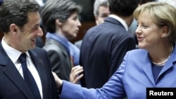 French President Nicolas Sarkozy talks with German Chancellor Angela Merkel at the start of an EU summit in Brussels on March 25.