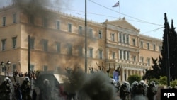 Riot police stand guard next to a Molotov cocktail thrown by protesters outside the Greek parliament building during a demonstration in Athens on March 11.