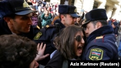 Police officers block activists during a rally held to support women's rights and to protest against violence toward women on International Women's Day in Baku on March 8.