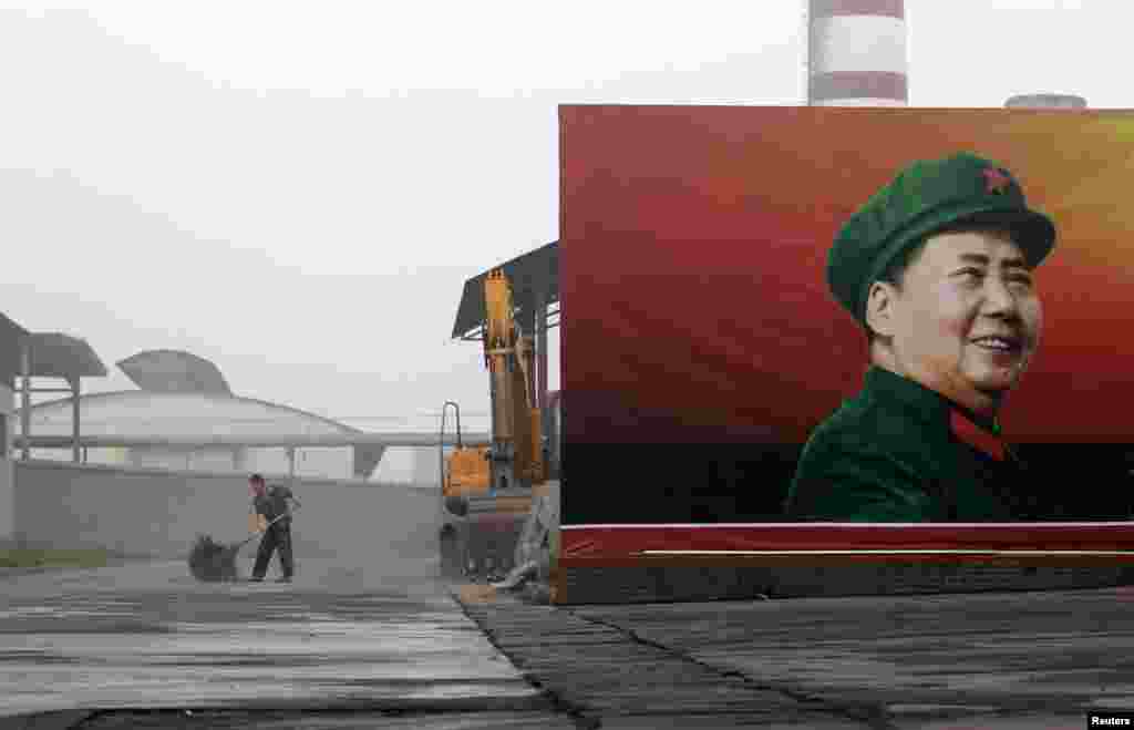 A worker cleans near a poster of the late Chairman Mao Zedong at a thermal power plant in Henan Province.