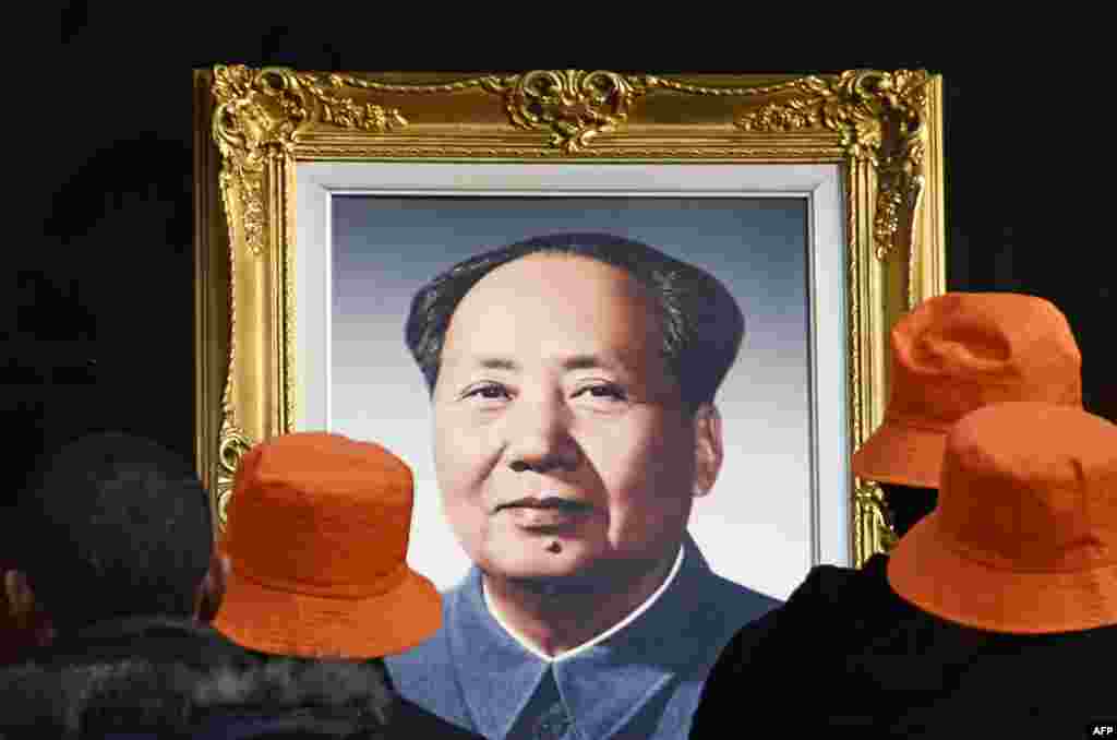 People look at a portrait of former Chinese leader Mao Zedong at a studio in Beijing.