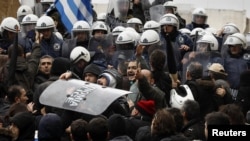 Anti-austerity protesters carry a police shield during scuffles in front of the parliament in Athens on February 7, when two of the largest Greek public sector unions went on a 24-hour strike.